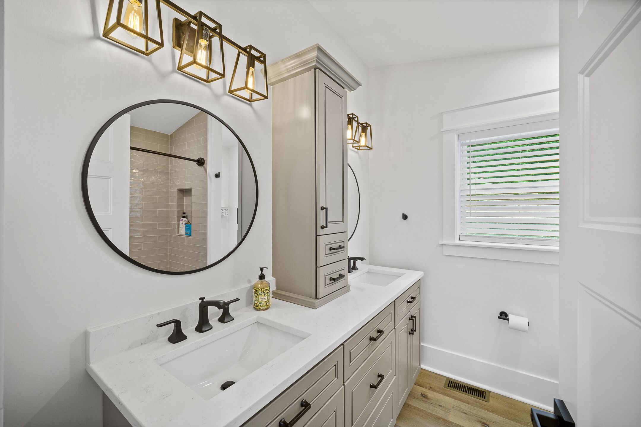 A bathroom with a double sink, a large mirror, and a cabinet with drawers.