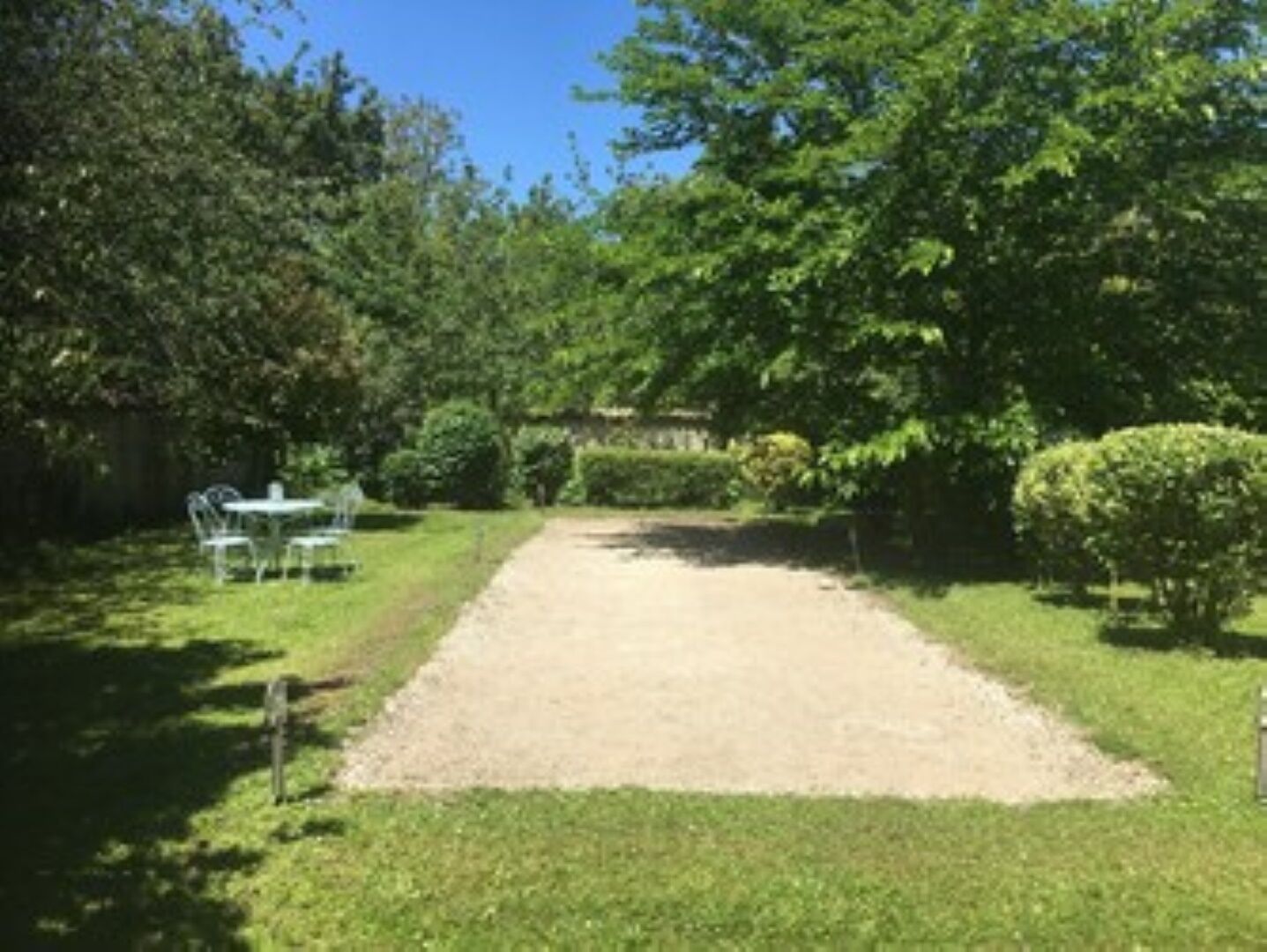 A garden with a gravel path, a table, and chairs.