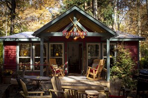A cabin with a porch, wooden chairs, and a table.