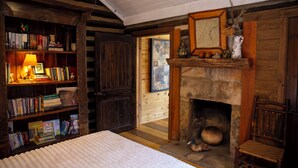 Una habitación acogedora con chimenea, estanterías de madera, una cama y un sillón.