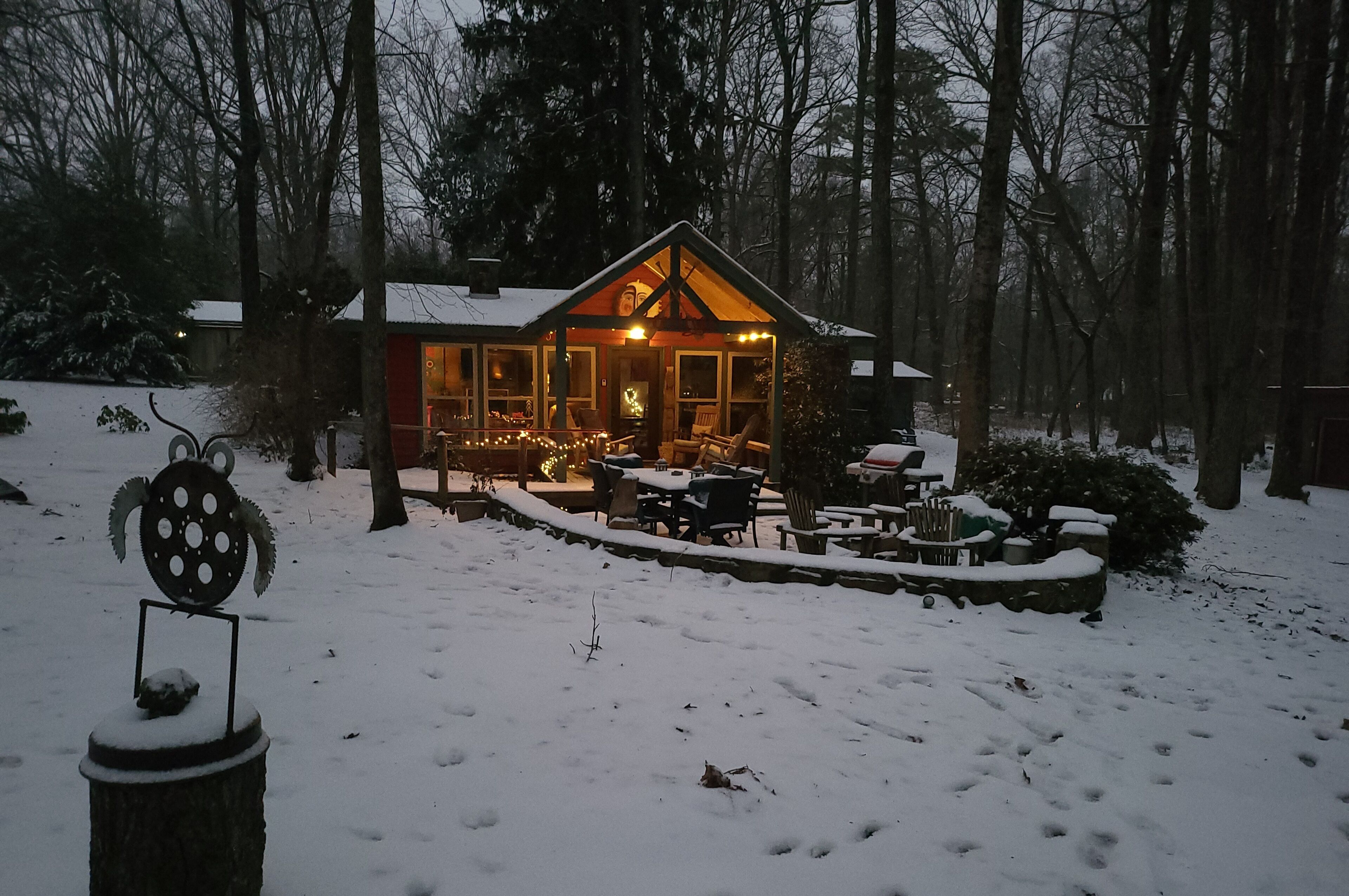 A cozy cabin with a wooden exterior, large windows, and a porch area with outdoor seating.