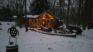 A cozy cabin with a wooden exterior, large windows, and a porch area with outdoor seating.