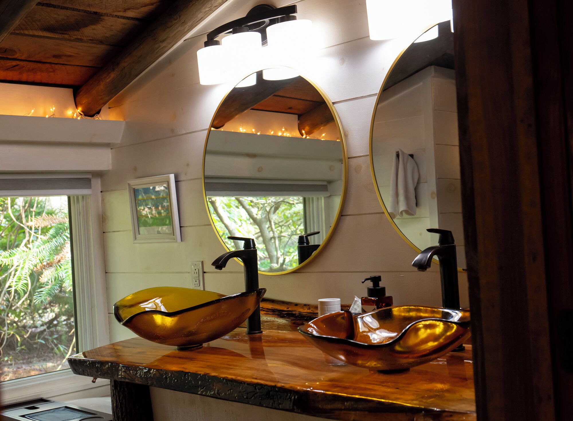 A bathroom with a wooden vanity, a large oval mirror, and a bowl sink.