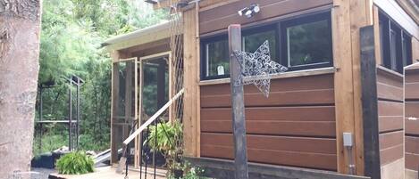 A wooden cabin with a deck, potted plants, and a star decoration.
