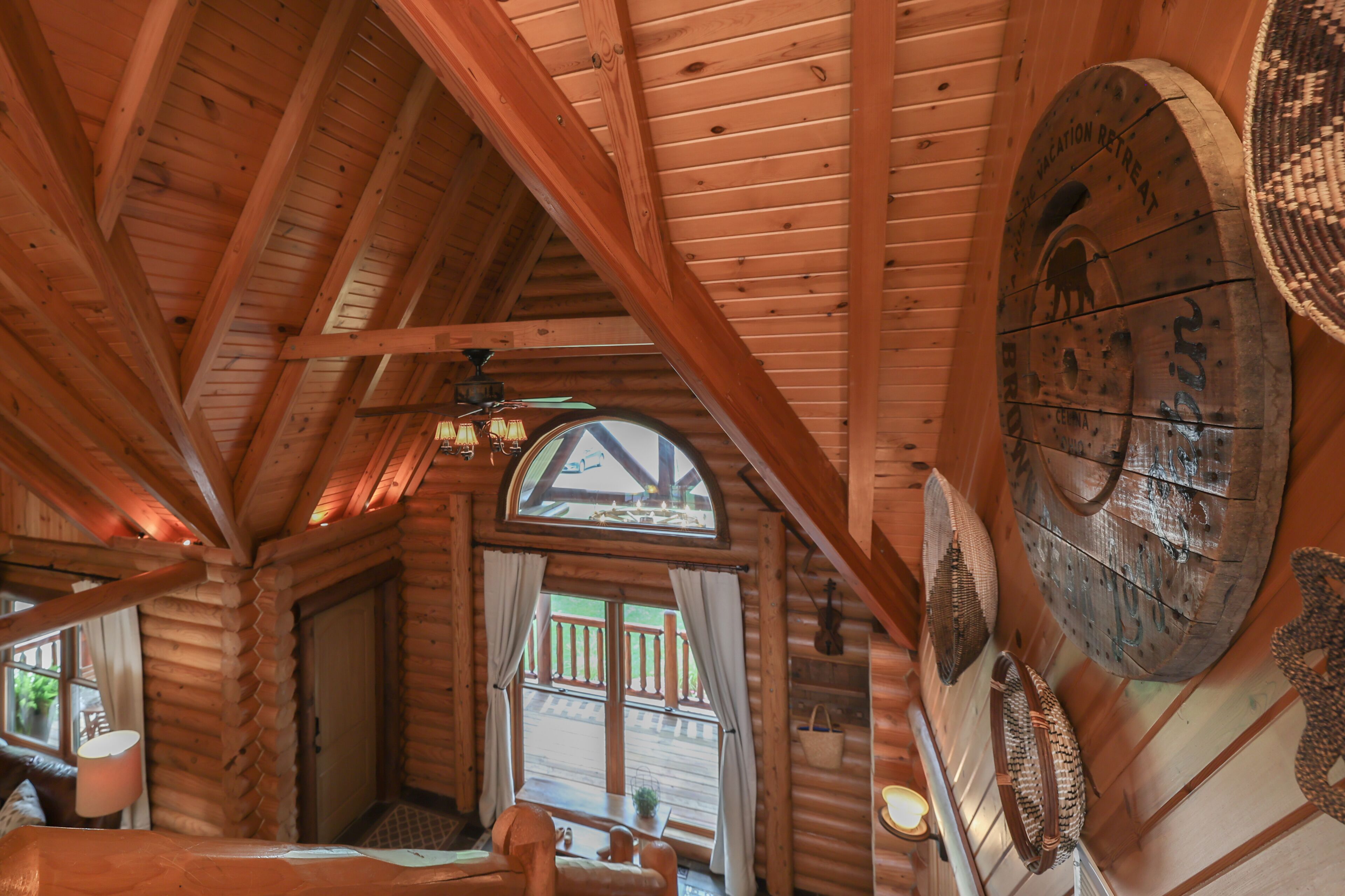L’intérieur d’une cabane en rondins, avec un plafond en bois, une grande fenêtre et une décoration murale rustique.
