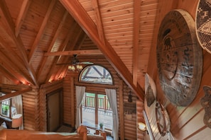 A log cabin interior with a wooden ceiling, a large window, and a rustic wall decor. - Heated Seasonal Pool, Hot Tub & Theater • Rustic Cabin by Bike Path (Celina)