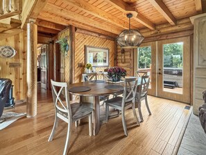 A wooden interior with a dining table, chairs, and a hanging light fixture. - Heated Seasonal Pool, Hot Tub & Theater • Rustic Cabin by Bike Path (Celina)