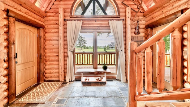 A log cabin interior with a wooden door, a bench with shoes, and a view of the outside. - Heated Seasonal Pool, Hot Tub & Theater • Rustic Cabin by Bike Path (Celina)