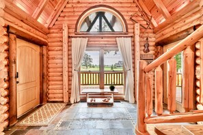 A log cabin interior with a wooden door, a bench with shoes, and a view of the outside. - Heated Seasonal Pool, Hot Tub & Theater • Rustic Cabin by Bike Path (Celina)