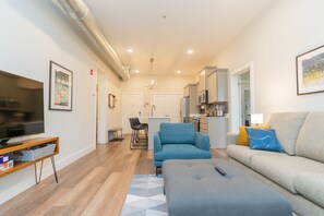 Relax in this stylish living space with a flat-screen TV, comfortable sofa, and a cozy armchair.