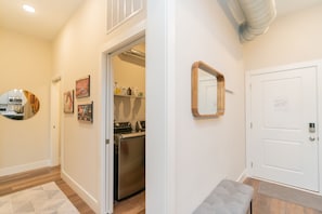 Enter a stylish hallway with a well-lit entrance, seating area, and convenient self-service laundry facilities.