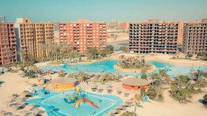 Un complexe hôtelier doté de plusieurs piscines, de palmiers et, en arrière-plan, de bâtiments de grande hauteur.