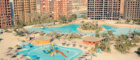 A resort with multiple swimming pools, palm trees, and high-rise buildings in the background.