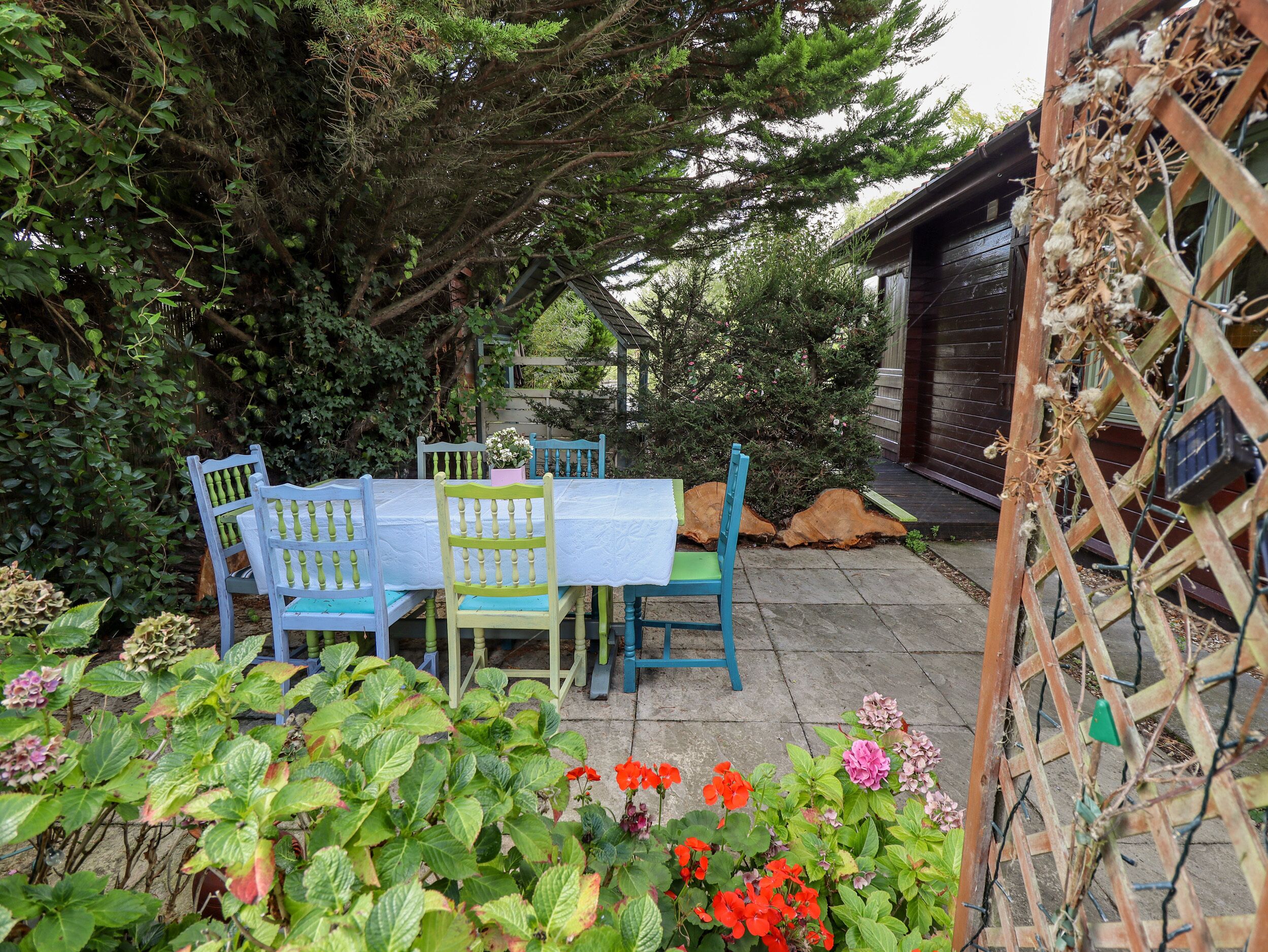 A patio with a table and chairs, surrounded by plants and a wooden fence.