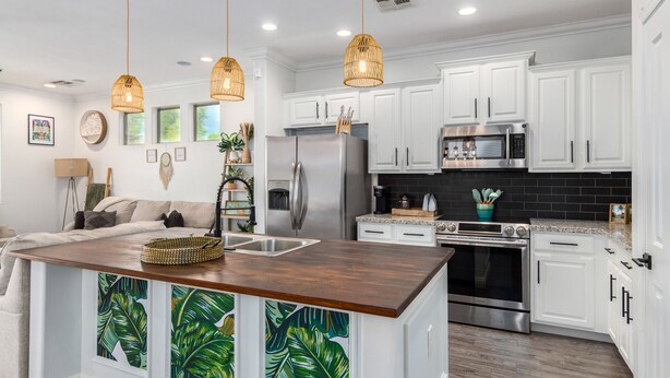 A modern kitchen with white cabinets, stainless steel appliances, and a wooden island with a tropical leaf backsplash. - Modern Island Getaway with Heated pool added fee, Bar & Gazebo (Gilbert)