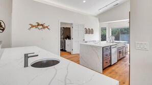 A modern kitchen with marble countertops, a built-in sink, and a view to the outside. - Sedona Gecko Retreat: Luxurious 4BR home with red rock views and private pool. (Sedona)