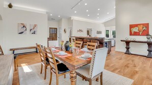 A spacious dining area with a wooden table and chairs, a kitchen in the background, and artwork on the walls. - Sedona Gecko Retreat: Luxurious 4BR home with red rock views and private pool. (Sedona)
