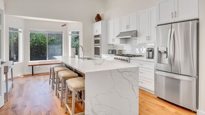A modern kitchen with white cabinetry, a marble island, stainless steel appliances, and a view to the outdoors. - Sedona Gecko Retreat: Luxurious 4BR home with red rock views and private pool. (Sedona)