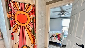 Une chambre d’hôtel avec un lit, un ventilateur de plafond et une salle de bain avec un rideau de douche.
