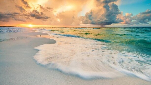 Une plage avec des vagues et un coucher de soleil.