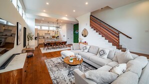 A spacious living area with a sofa, coffee table, and a staircase. - Luxury Midtown Houston Home w/ Rooftop Skyline Views (Houston)
