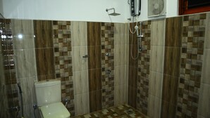 A bathroom with a toilet, shower, and tiled walls. - Dream Weaver Eco Homestay Sigiriya (Sigiriya)