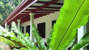 A covered porch with white pillars and a red roof, surrounded by lush green foliage. - Dream Weaver Eco Homestay Sigiriya (Sigiriya)