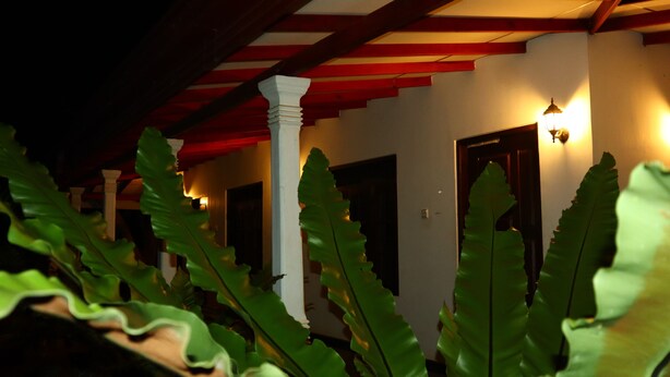 A corridor with a wooden ceiling and a wall-mounted light fixture. - Dream Weaver Eco Homestay Sigiriya (Sigiriya)