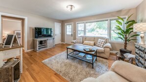 A living room with a sofa, coffee table, television, and a plant.