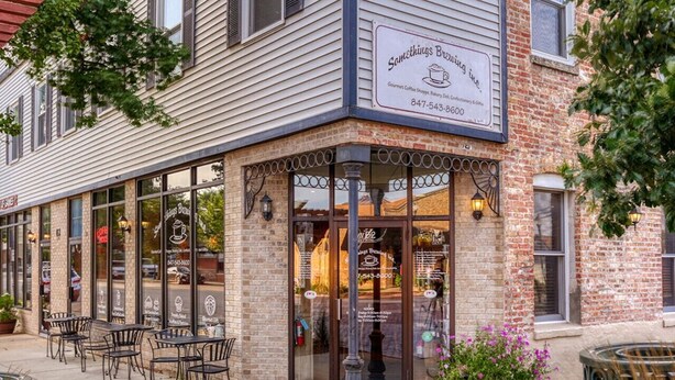 A corner building with a sign reading "Something Brewing." It has large windows and outdoor seating.