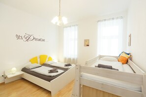 Een kamer met twee bedden, een nachtkastje met een lamp, een wandklok en een decoratief bord aan de muur.