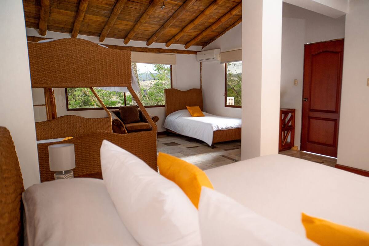 Une chambre avec deux lits, un plafond en bois et une vue sur la verdure.