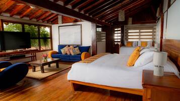A spacious room with a large bed, a sofa, a television, and a wooden ceiling.