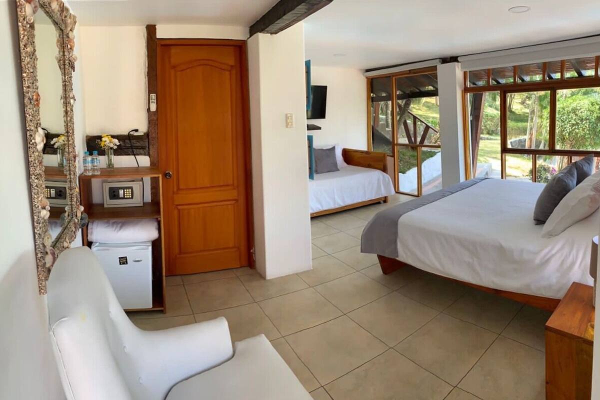Une chambre à coucher avec un lit, une chaise, un bureau, un miroir et une porte.