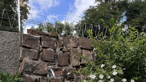 Une baignoire blanche avec un robinet, un mur en pierre et des fleurs blanches en arrière-plan.