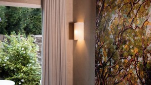 Une salle de bain moderne avec un grand tableau représentant des arbres, une baignoire blanche et un rideau.
