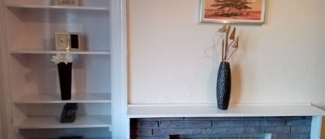Una habitación con chimenea, una estantería y un cuadro en la pared.