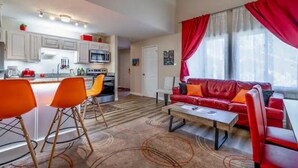 Een moderne woonkamer met een rode bank, oranje fauteuils en een salontafel.