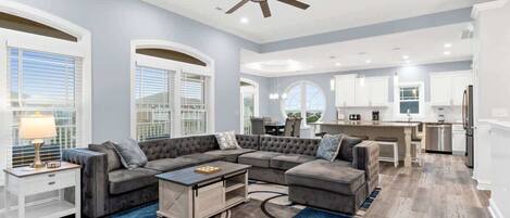 A spacious living room with a sectional sofa, a coffee table, and a ceiling fan.