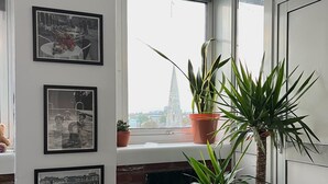 A room with a brick fireplace, a window with a view of a cityscape, and three framed photographs on the wall. - Fantastic View over London apartment in Abbey Road (London)