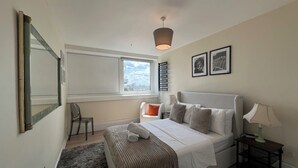 A bedroom with a bed, bedside table, lamp, chair, window, and a view of the city. - Fantastic View over London apartment in Abbey Road (London)