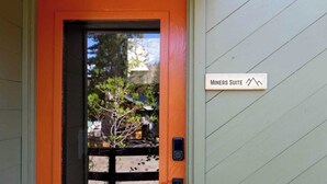 Une porte sur laquelle est apposée une plaque indiquant « Suite des mineurs », et une petite fenêtre qui reflète des arbres et un bâtiment.