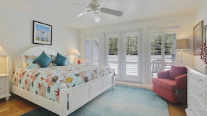 Ein Schlafzimmer mit Bett, Stuhl, Schminktisch und Deckenventilator.