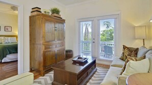 Un salon avec un meuble en bois, un canapé, une table basse et une vue à travers les portes vitrées.
