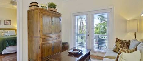 A living room with a wooden cabinet, a sofa, a coffee table, and a view through the glass doors.