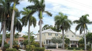 Un quartier résidentiel avec des maisons, des palmiers et une entrée sécurisée par un portail.
