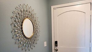 A hallway with a decorative mirror on the wall and a white door. - OKC - Curtis · Self Check-in-King-Fast wifi-20min 2 anywhere (Oklahoma City)