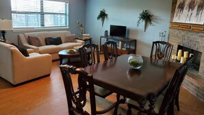 A living room with a sofa, dining table, chairs, a fireplace, and a television. - OKC - Curtis · Self Check-in-King-Fast wifi-20min 2 anywhere (Oklahoma City)