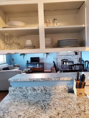 A kitchen with granite countertops, a knife block, and a dining area with chairs and a table.