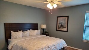 A bedroom with a large bed, a ceiling fan, a nightstand, a lamp, and a framed picture on the wall. - OKC - Curtis · Self Check-in-King-Fast wifi-20min 2 anywhere (Oklahoma City)